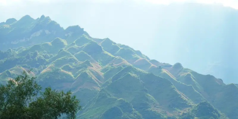 Green mountain ridges in northern Vietnam under broken cloud with light falling across the slopes