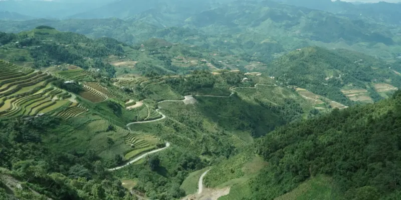 Terraced valleys and a winding road in northern Vietnam seen from a high viewpoint under a wide sky