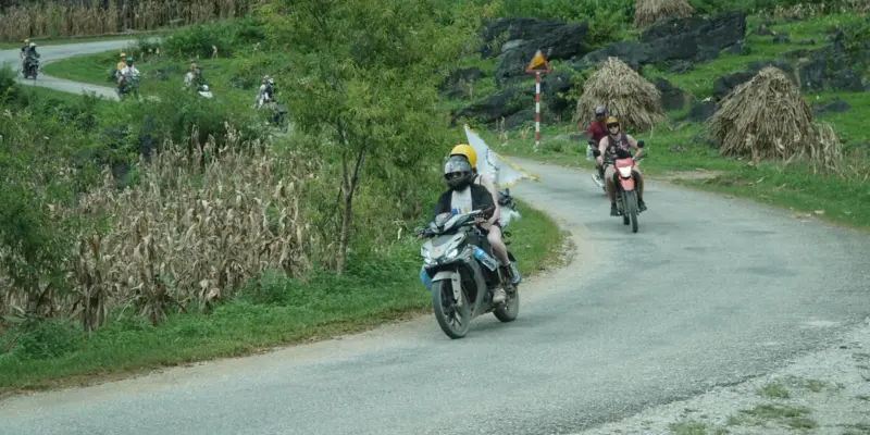 A loaded motorbike with a soft bag strapped behind the rider on a mountain road in northern Vietnam