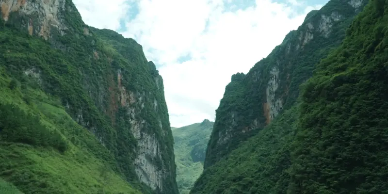 The Nho Que river between steep canyon walls in Ha Giang, a small boat far below on green water