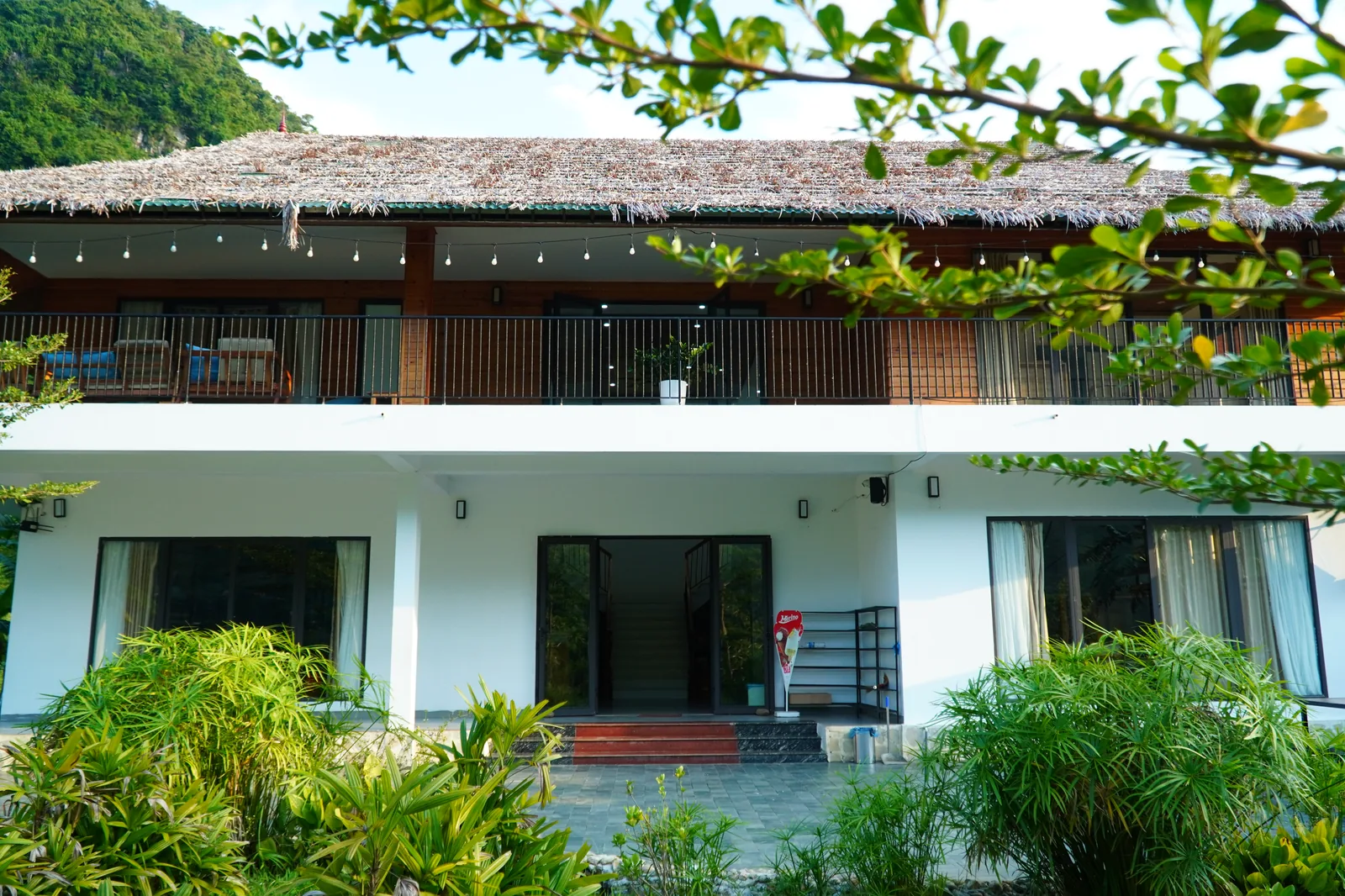 The white room block at Jashill Homestay under a thatched roof, Du Gia, August 2026