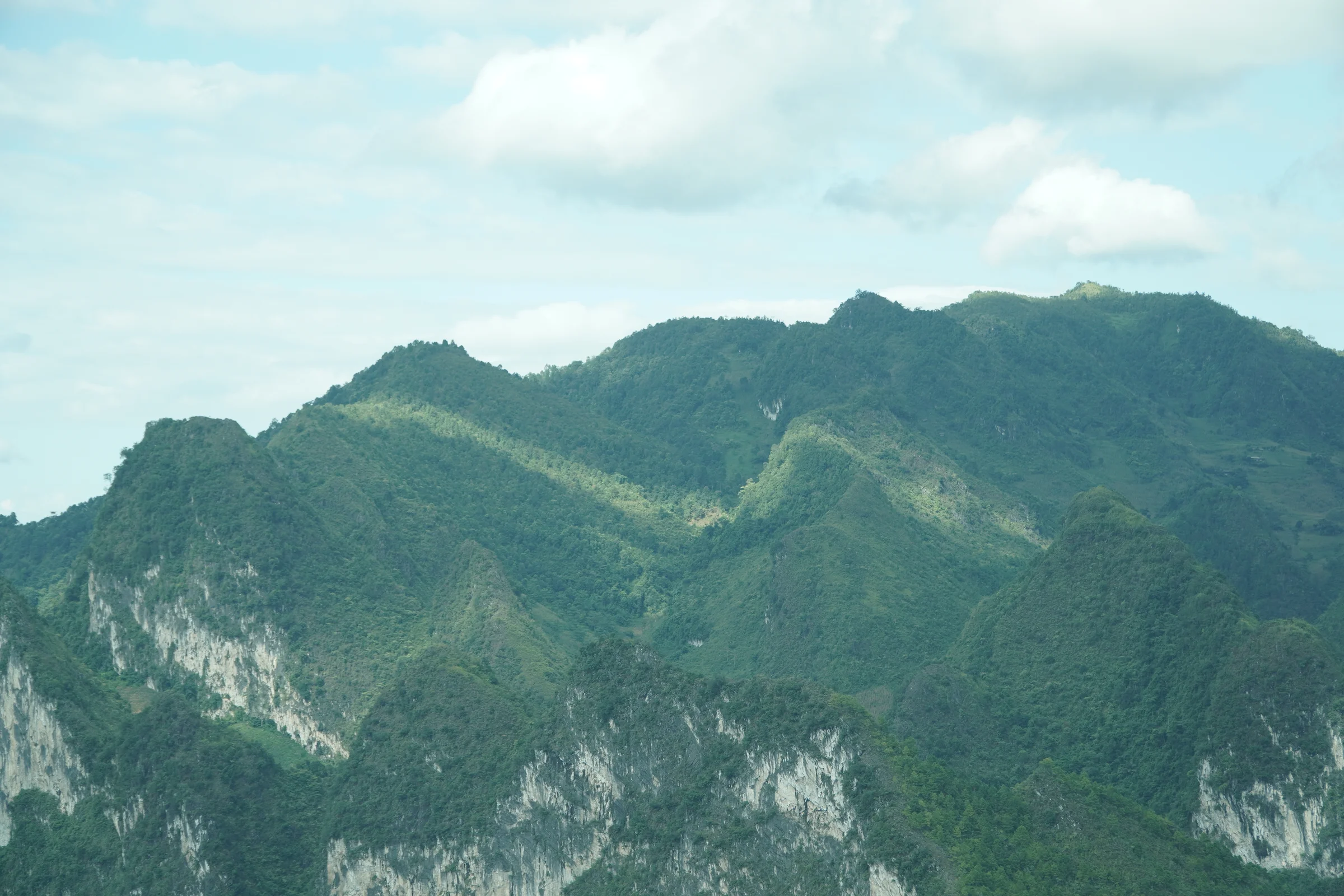Limestone karst ridges and a green valley floor in Ha Giang province under scattered cloud