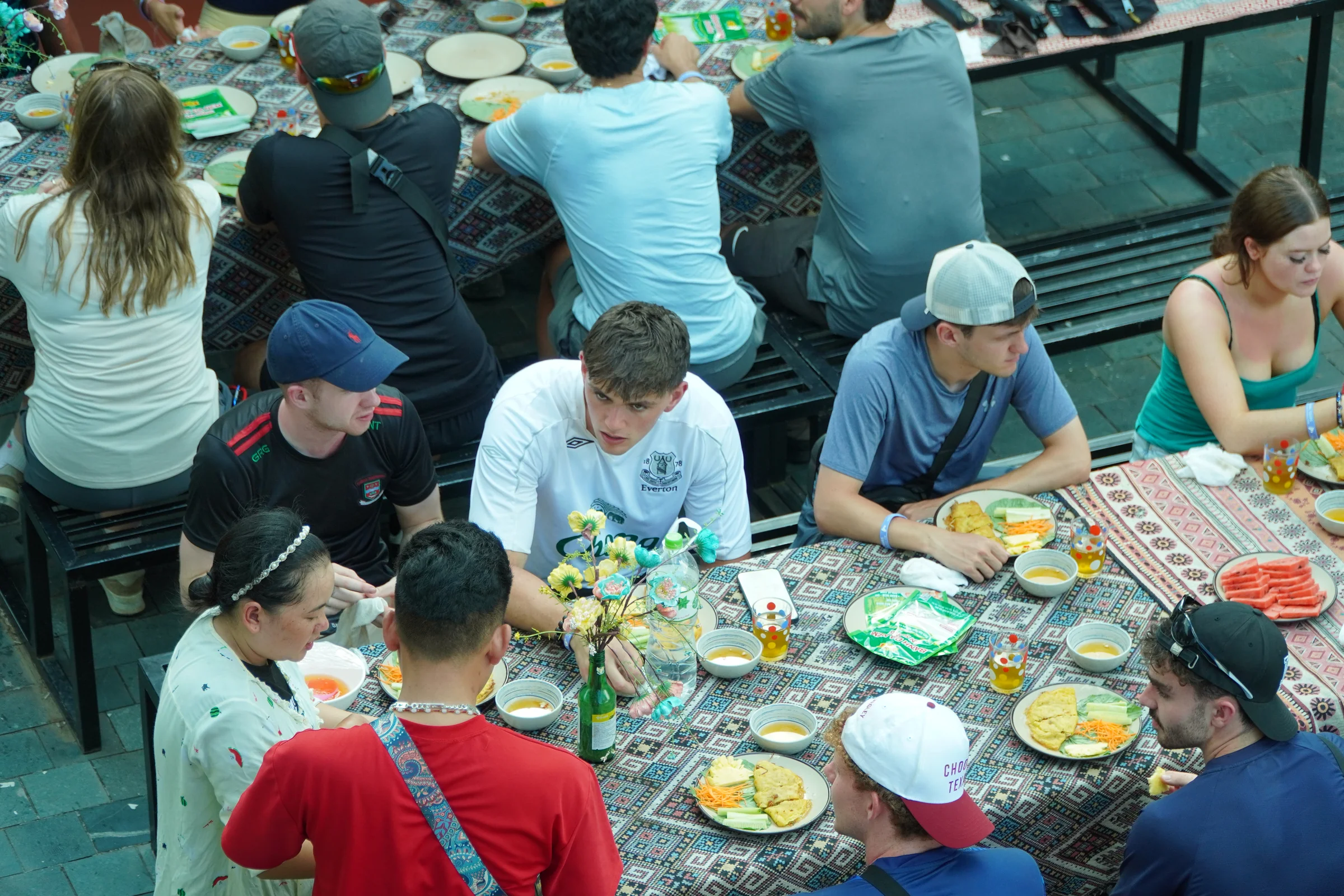 A shared table of food at a roadside stop in Ha Giang, travellers and local guides eating together