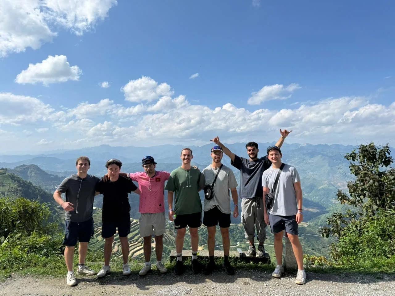 A group of travellers standing together at a viewpoint above green mountains in Ha Giang, May 2026