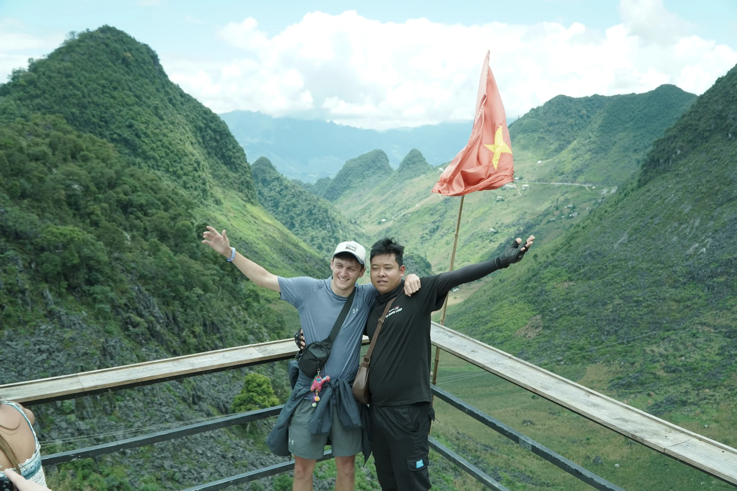 A road curving through green karst mountains in northern Vietnam under broken cloud