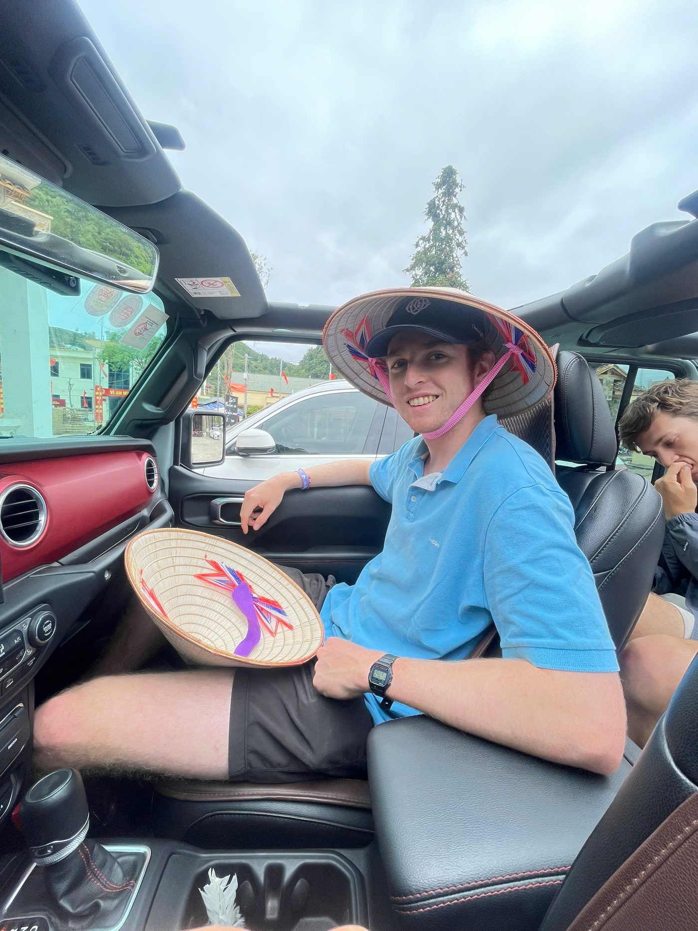 A traveller wearing a conical hat in a van on the road north to Ha Giang
